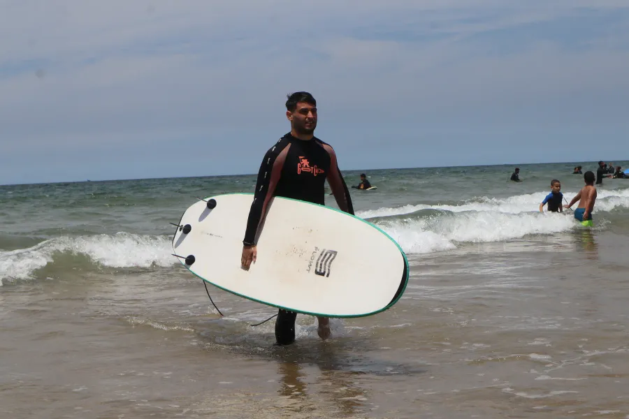 Surfer carrying a white board out of the water