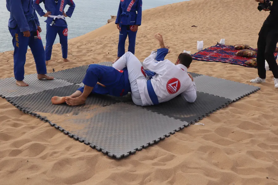 Two participants drilling in gis on mats laid on the sand