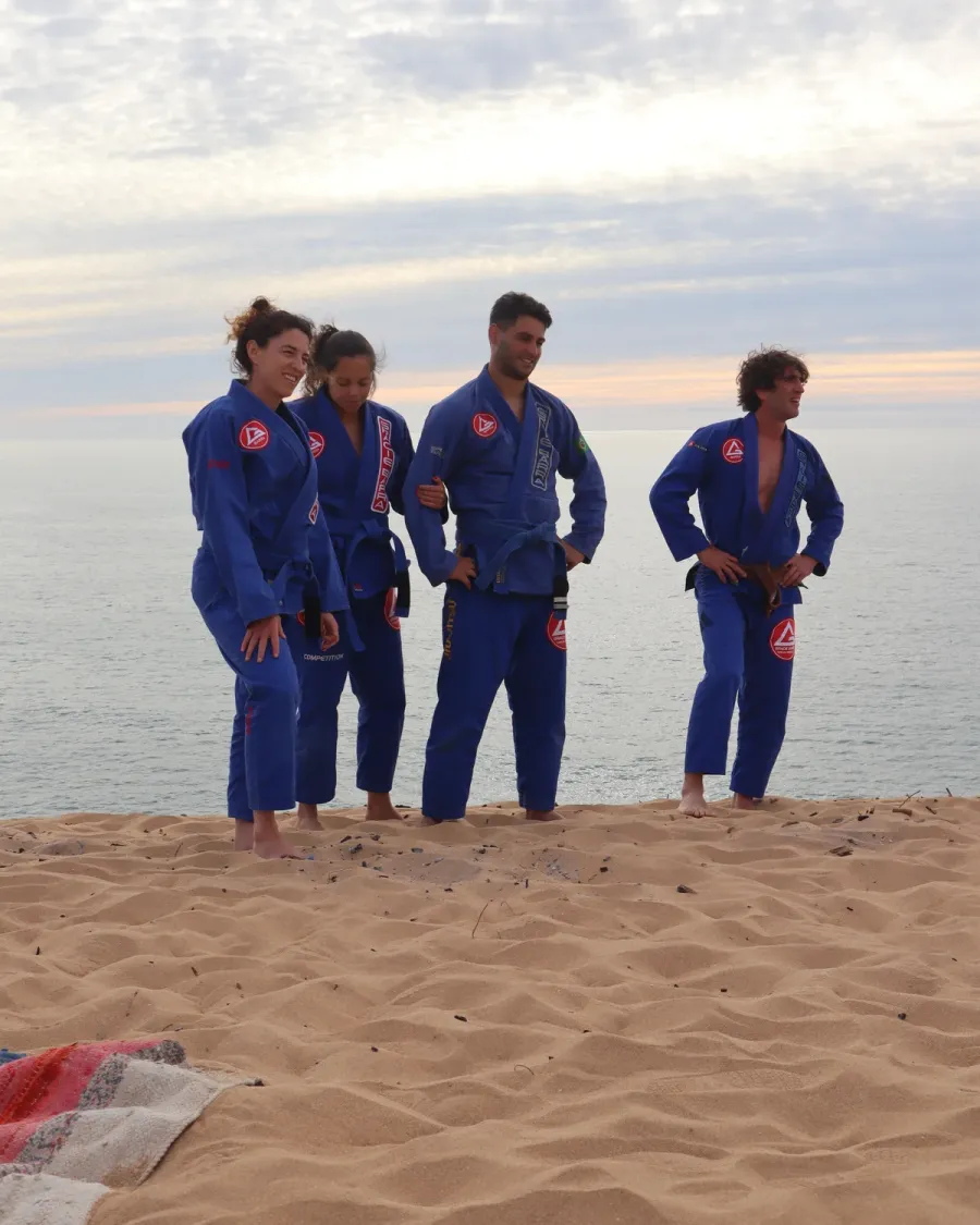 Three training partners in blue gis standing on the beach
