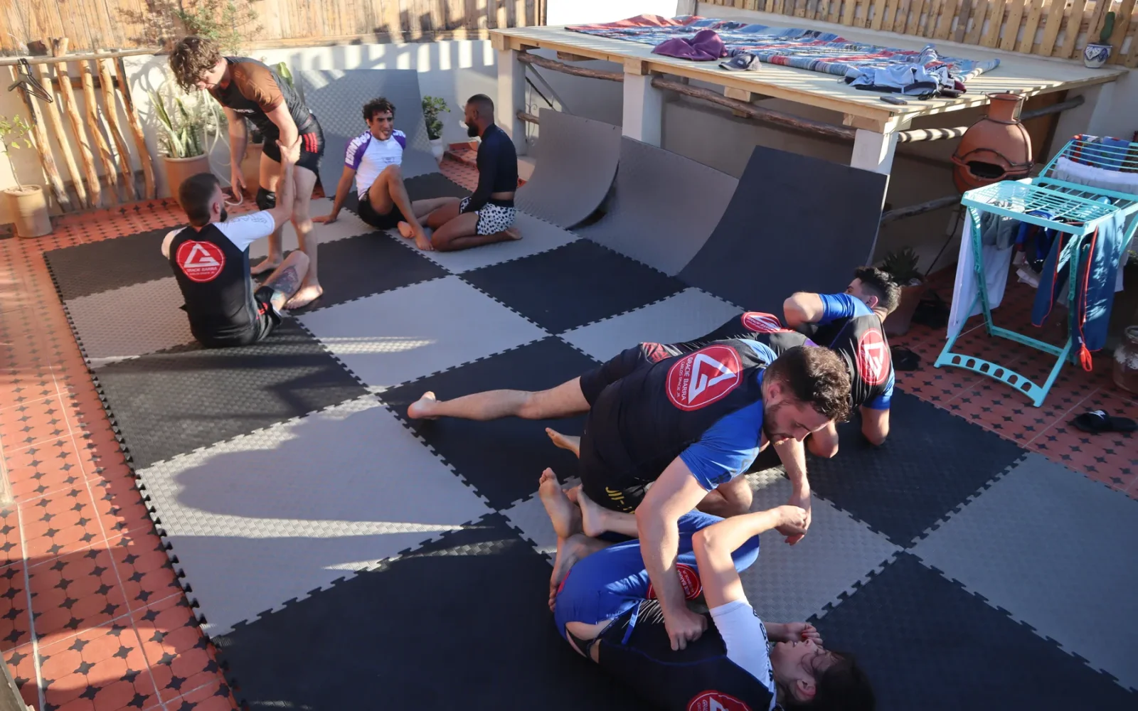 Several pairs practising jiu-jitsu on a rooftop mat area — previous MatnWave edition