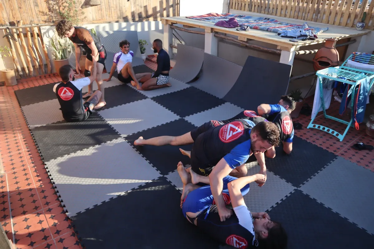 Several pairs practising jiu-jitsu on a rooftop mat area
