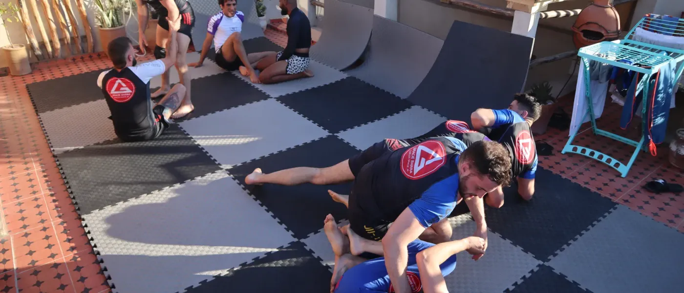 Several pairs practising jiu-jitsu on a rooftop mat area