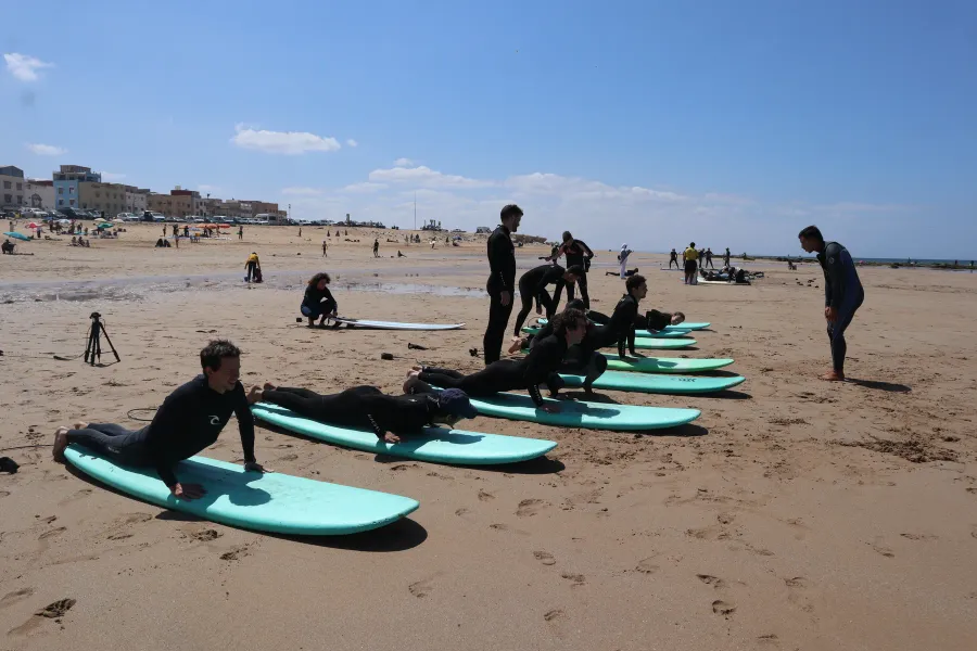Participants practising on surfboards laid out on the beach