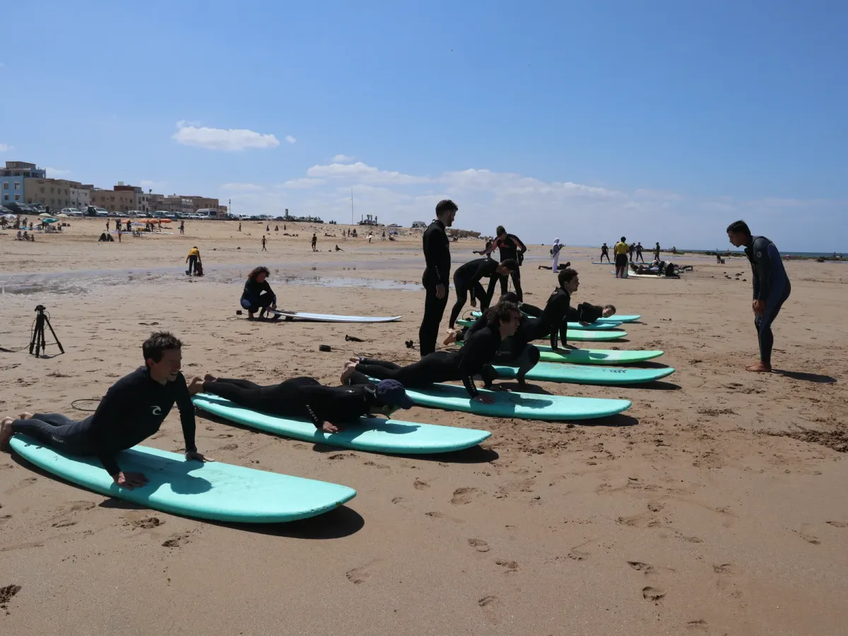 Participants practising on surfboards laid out on the beach
